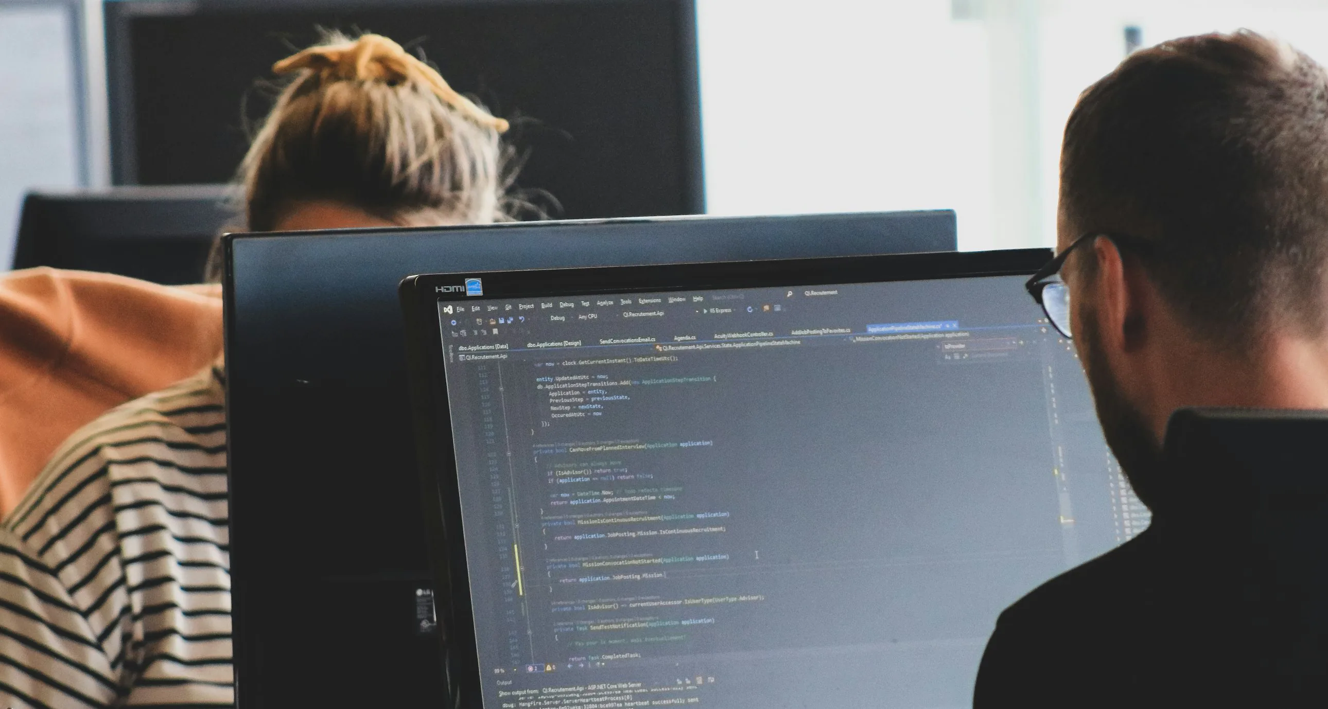 Two developers working with code on their screens