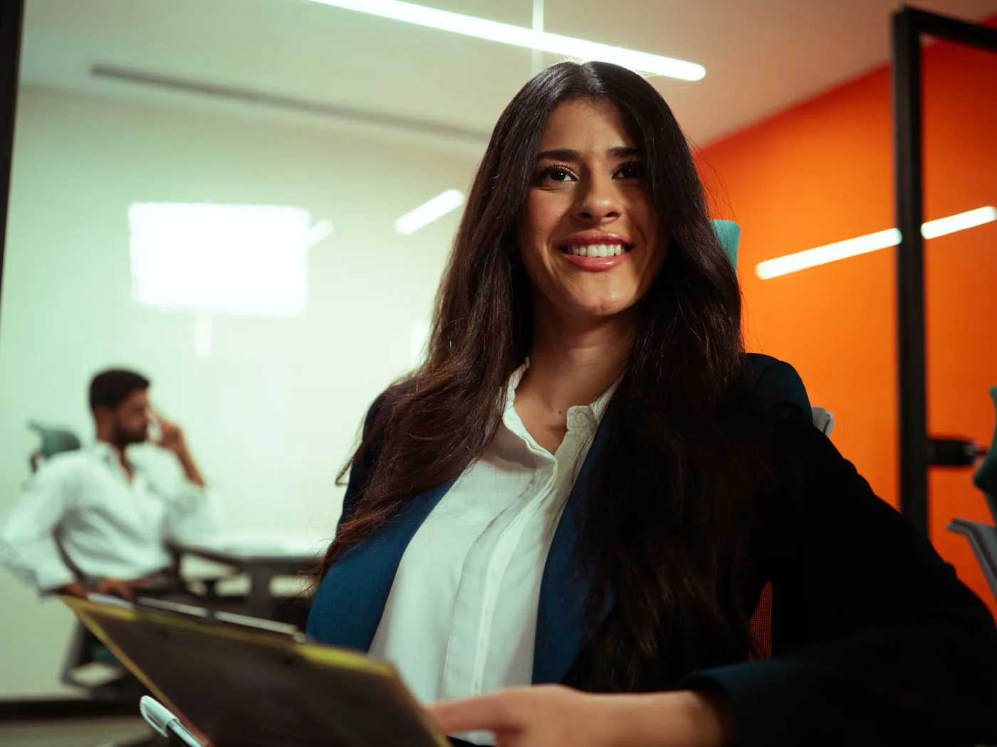A smiling professional holding a tablet in an office